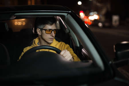 Man driving car in special yellow eyeglasses at night for good night visionの写真素材