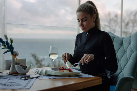 Luxury woman eating cake in restaurant with sea viewの写真素材