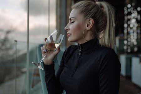 Luxury woman drinking white wine sitting in restaurant with sea view