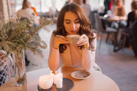 Portrait of young woman drinking coffee sitting in a beautiful cafeの写真素材