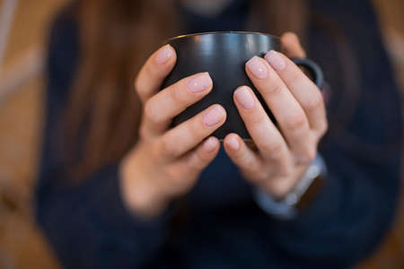 Girl's nails with beautiful manicure holding cup of teaの写真素材