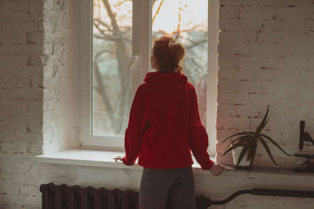 At home alone, woman looking through windowの写真素材