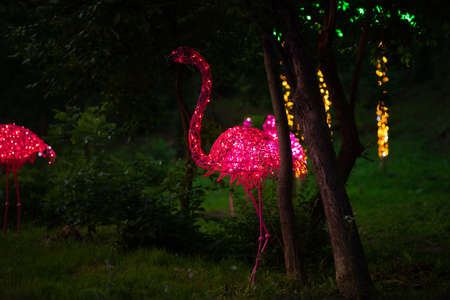 Decorative pink flamingo glows in a night park, beautiful decoration of green zoneの写真素材
