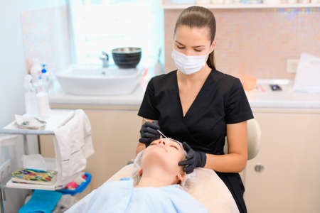 Beautician cleaning clients face using acne removal cosmetic spoon in a beauty salon