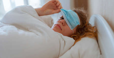 Woman sleep with surgical mask on her eyes, coronavirus conceptの写真素材