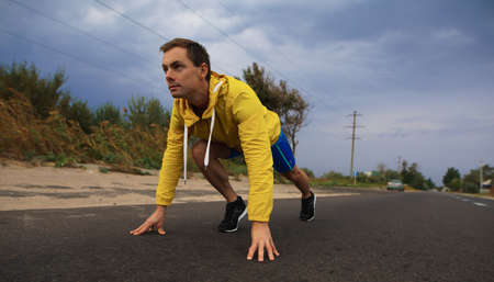 Runner man ready to run on the road from a low start