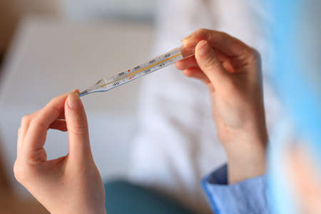 Closeup female hands holding thermometer with normal temperature in the bed