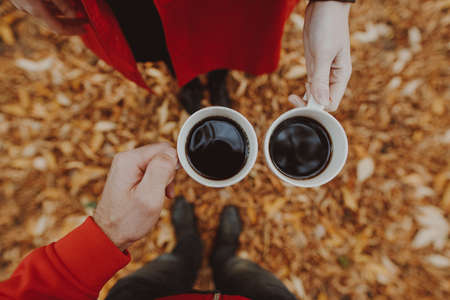 POV, couple holding cup with coffee at the fall dayの写真素材