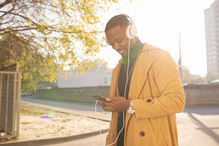 African American man listening to music with headphones on head walking in city