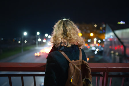 Woman looking at the night city view from the bridge