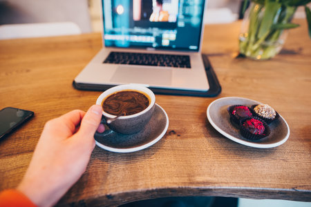 POV, freelancer working in a cafe drinking coffee, laptop on backgroundの写真素材