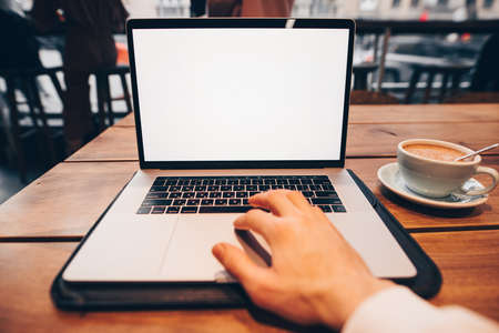 Male hand working by laptop computer with empty screen in a cafeの写真素材
