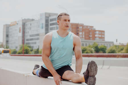 Sport man sitting in twine pose on the bridgeの写真素材