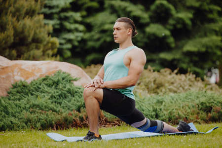 Man making yoga stretching exercise on grass in a parkの写真素材
