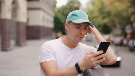 Man in cap using smartphone at the summer city