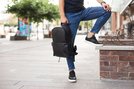 Man holding and demonstrate his new black leather backpack in a cityの写真素材