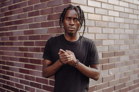 African man portrait with dreadlocks against brick wall backgroundの写真素材