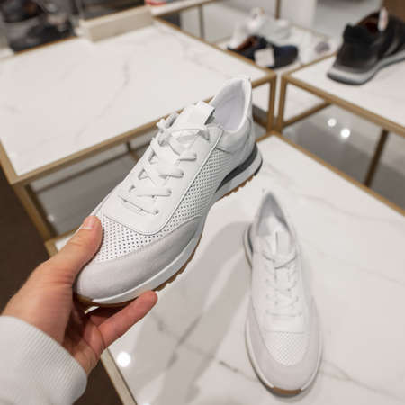 POV male hand choosing a new white sneakers in the shoes storeの写真素材
