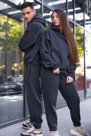 Stylish couple in grey pair costumes posing near the buildingの写真素材