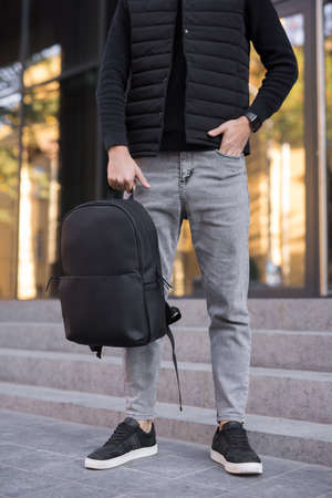 Unrecognizable man holding leather backpack in a cityの写真素材