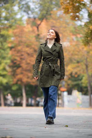 Happy woman walking at the autumn park enjoying an October dayの写真素材
