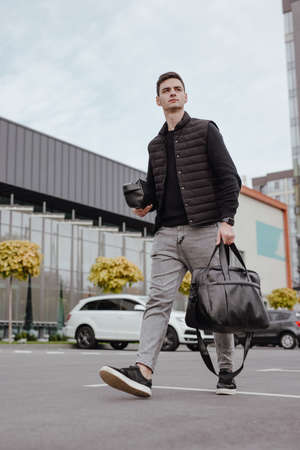Businessman walking in a city street with black leather bagの写真素材