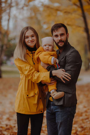 Happy young family portrait at the autumn park looks at the cameraの写真素材