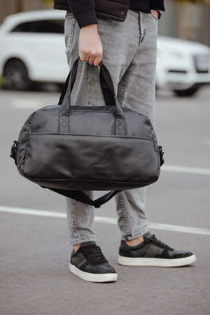 Unrecognizable man holding black bag in a city