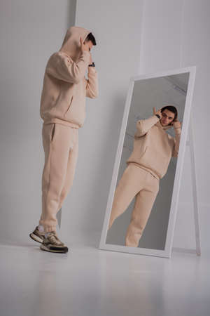 Man posing in studio wearing beige hoodie costumes near mirrorの写真素材