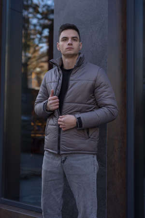 Man posing in city wearing grey winter jacketの写真素材