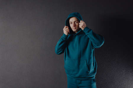 Handsome man wearing green hoody near wallの写真素材