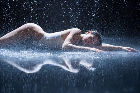 Sexy woman lying in aqua studio under rainの写真素材