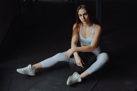 Sportive woman sitting on a floor in gym