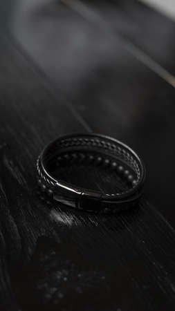 Black leather male bracelet on the dark wooden deskの写真素材