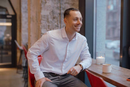 Handsome man in classical suit sitting in restaurant near windowの写真素材