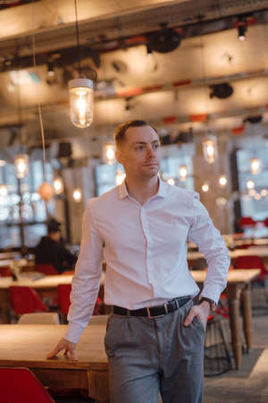 Handsome man in classical suit standing in restaurant, vertical portrait
