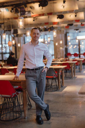 Handsome man in classical suit standing in restaurant, vertical portraitの写真素材
