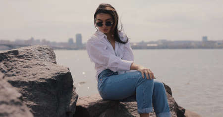 Woman sitting on the stones at the river and relaxes alone
