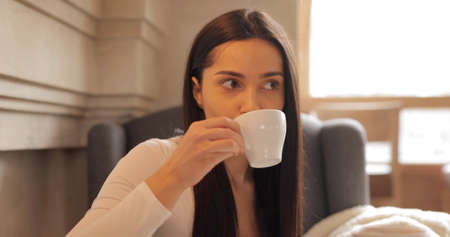 Pretty brunette woman drinking coffee in cafeの写真素材