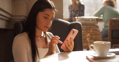 Beautiful brunette woman using smartphone in a cafeの写真素材