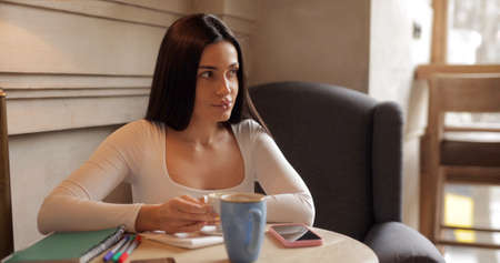 Pretty brunette woman drinking coffee in cafeの写真素材