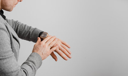 Man checking time on his wrist watch, grey backgroundの写真素材