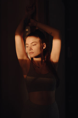 Pretty young woman creative portrait in the sunbeam at home, light and shadowの写真素材