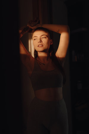 Pretty young woman creative portrait in the sunbeam at home, light and shadowの写真素材