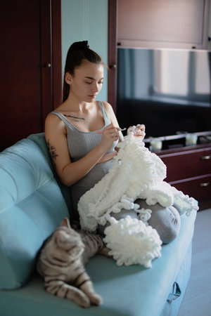 Young woman knitting plaid at homeの写真素材