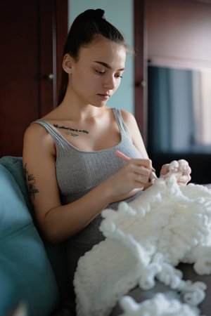 Young woman knitting plaid at homeの写真素材