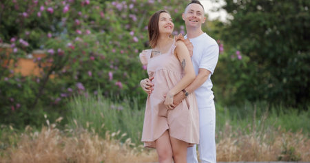 Young family, man hug his pregnant wife, they smiling together at the natureの写真素材