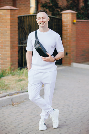 Stylish Caucasian man in white costume posing at the street with banana bagの写真素材