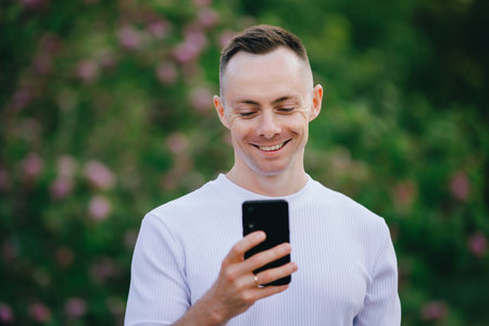 Closeup handsome Caucasian man looking at mobile phone in the summer dayの写真素材