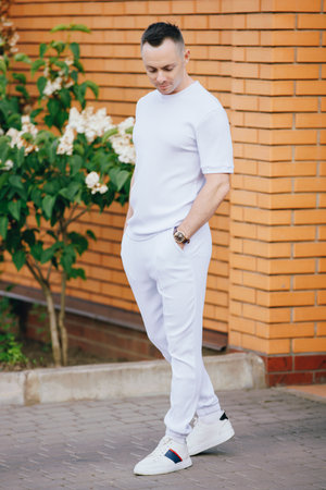 Handsome Caucasian man in fashionable white costume posing at the streetの写真素材